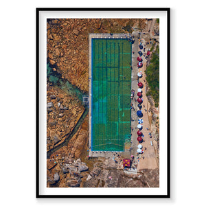 Aerial view of turquoise freshwater pool by rocky coastline with umbrellas and visitors, photography print by Remy Gerega