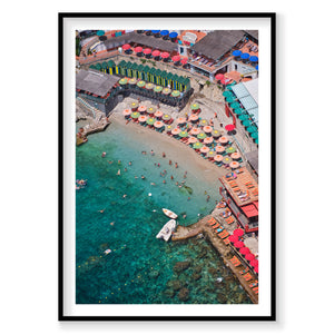 Aerial view of Bagni Internazionali Capri with colorful umbrellas and people in the water, framed artwork.