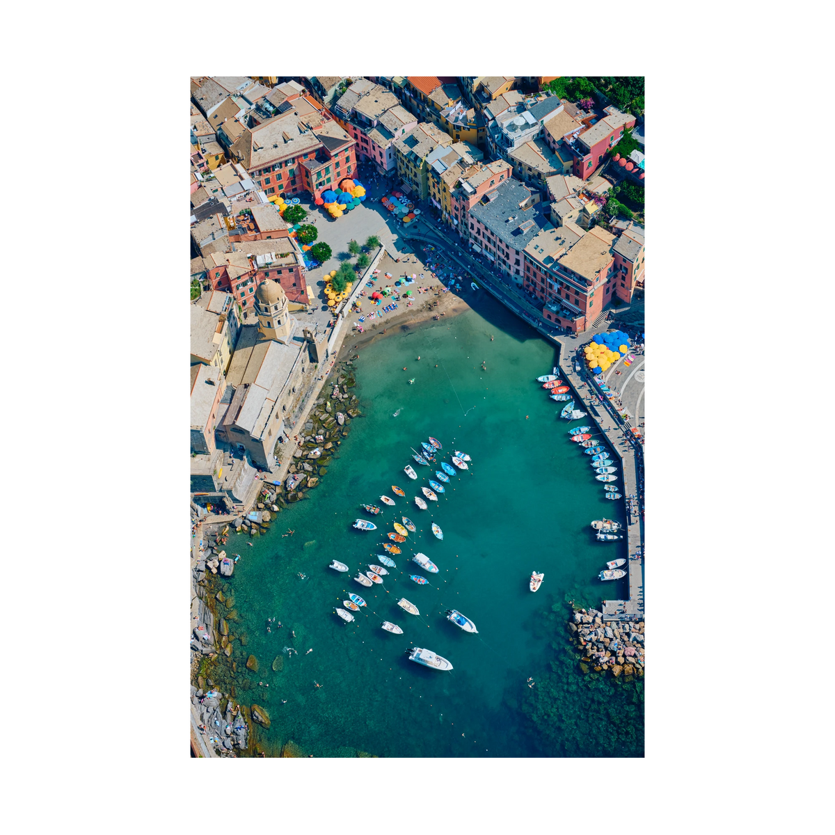 Overhead view of colourful waterfront buildings, a small beach, boats and swimmers in Vernazza harbour, Cinque Terre, Italy, print-only presentation.