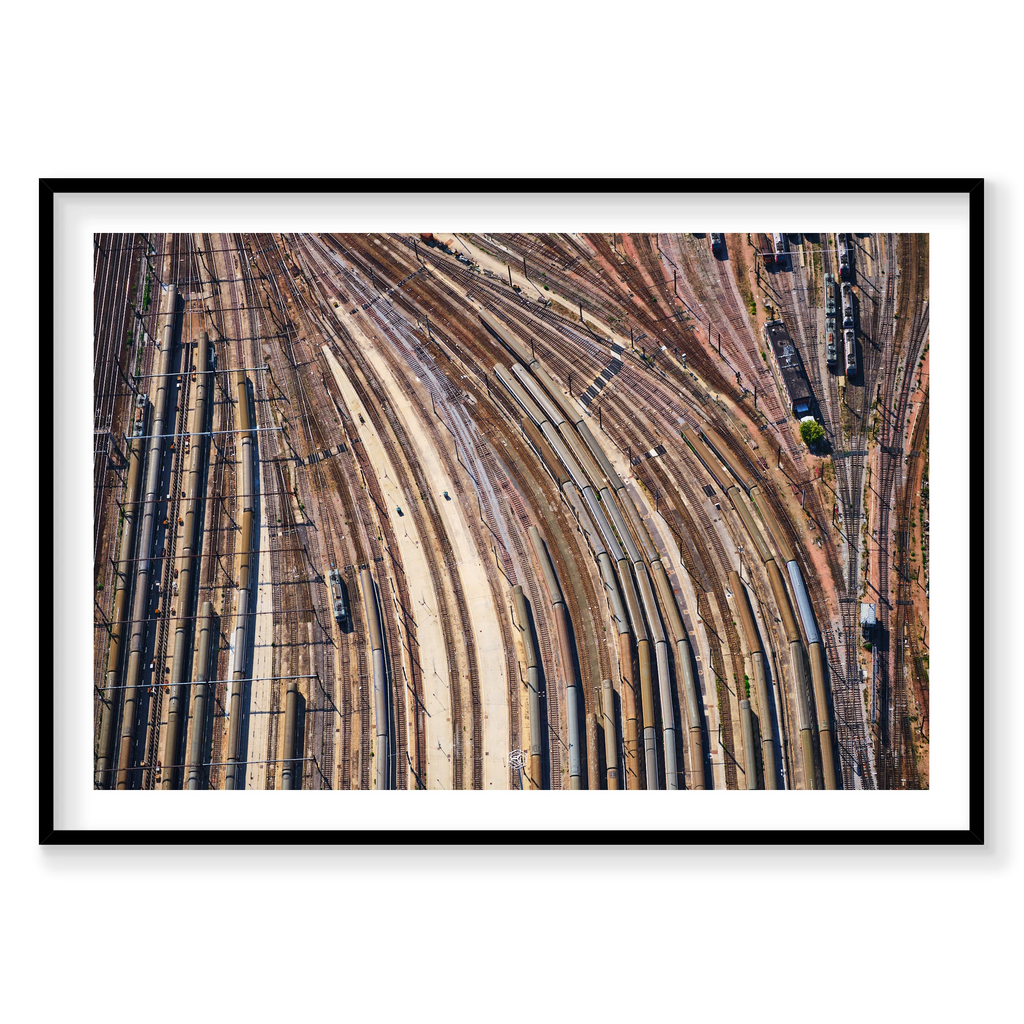 Aerial view of curving railway tracks and rows of train carriages in a rail yard in the Paris region, France; black frame
