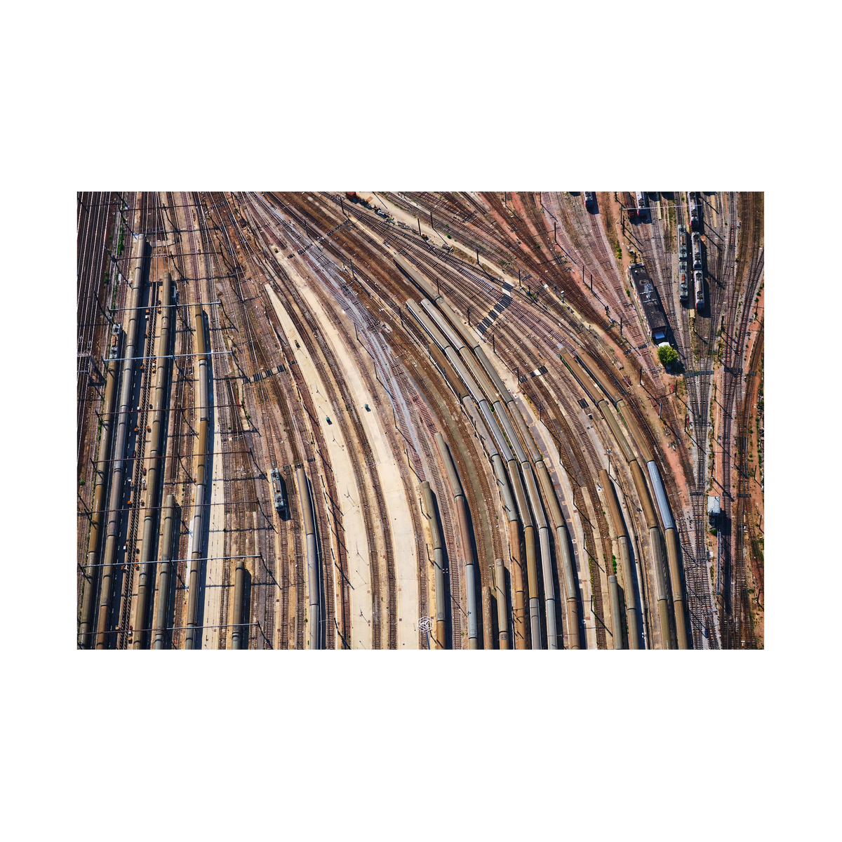 Aerial view of curving railway tracks and rows of train carriages in a rail yard in the Paris region, France; print only