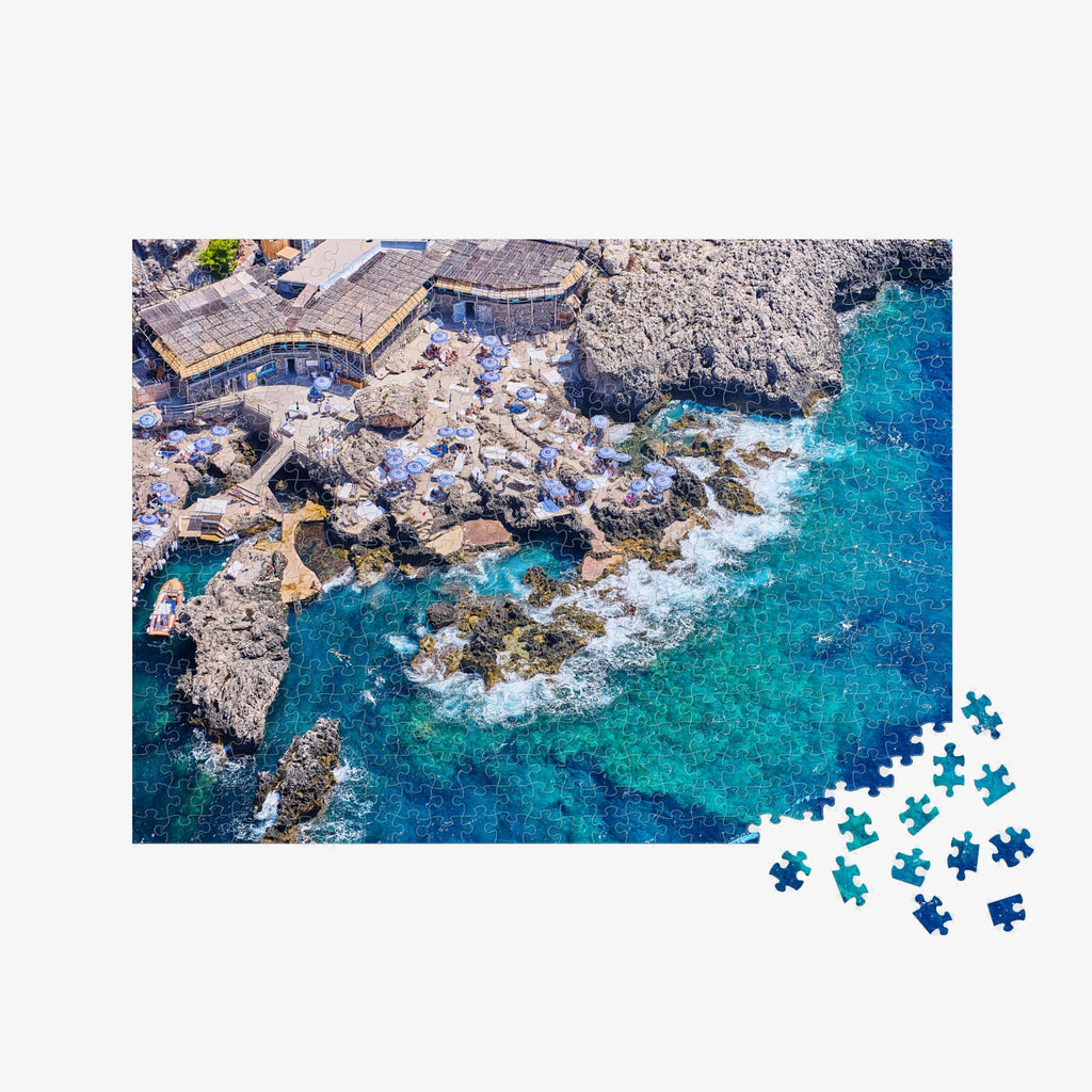 Aerial view of Capri's rocky coastline with turquoise waters and yellow beach umbrellas,500 piece jigsaw puzzle by Remy Gerega