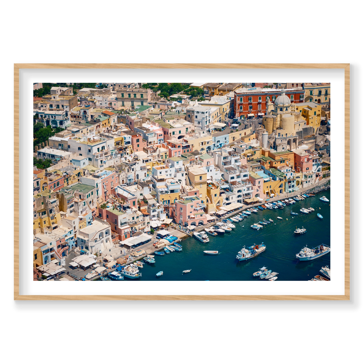 Pastel waterfront buildings, balconies and small boats on deep blue water in Procida, Italy, natural timber frame.