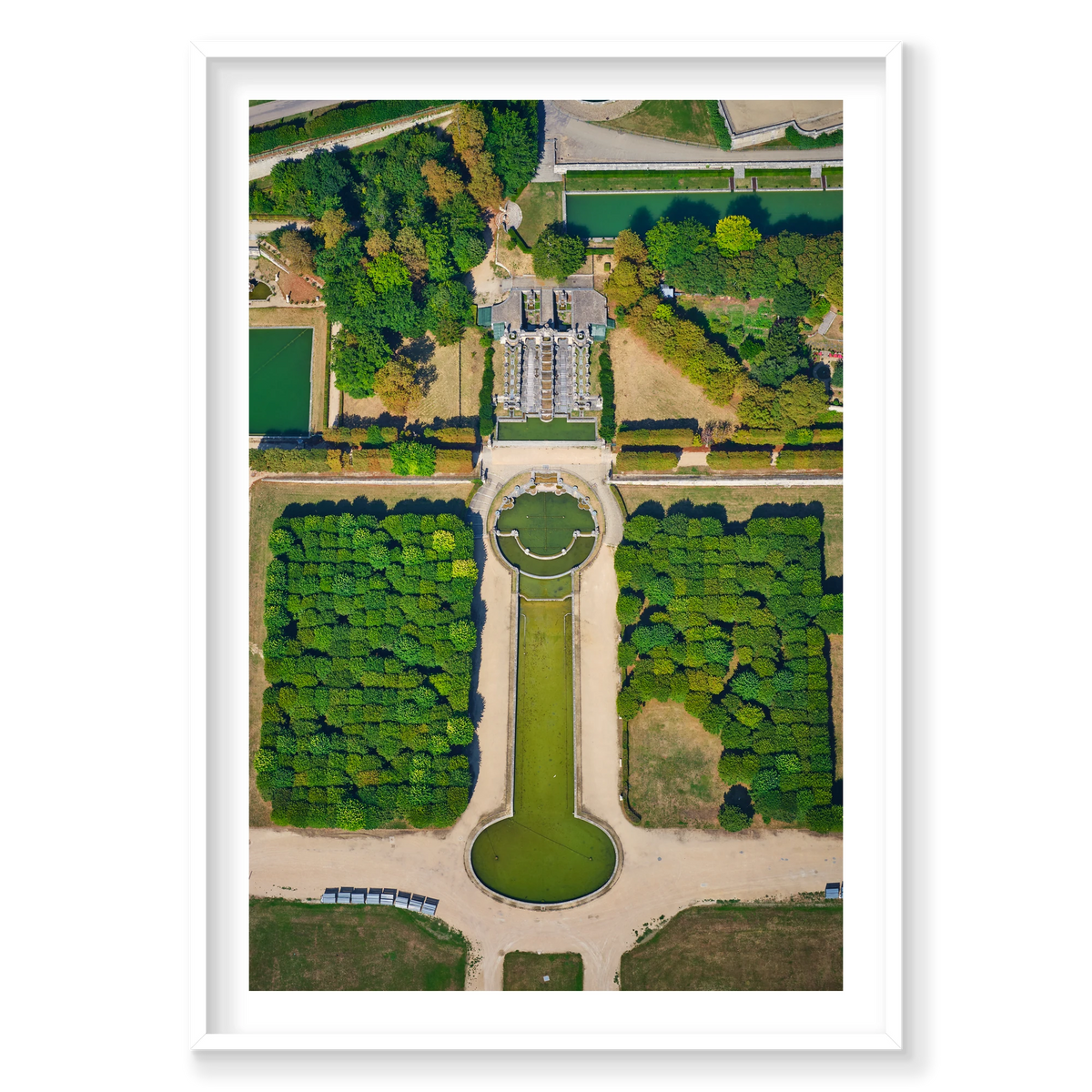 Overhead view of formal gardens in the Paris region, with green pools, pale paths, rows of trees and an ornate cascade; white frame