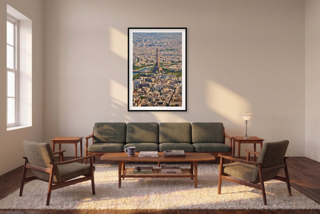 Vertical aerial photograph of the Eiffel Tower, the Seine and densely packed Paris rooftops extending into the distance; black framed print in a room setting