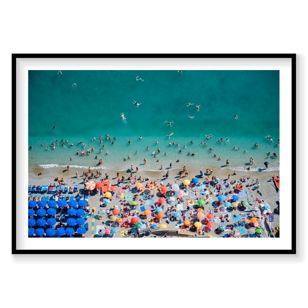 Swimmers in turquoise water beside colourful beach umbrellas at Monterosso al Mare, Cinque Terre, Italy, black frame.
