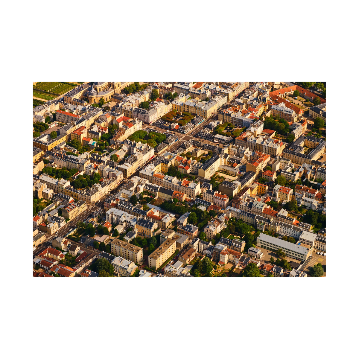 Aerial view of pale buildings, grey and red rooftops, courtyards and tree-lined streets in the Paris region, France; print only
