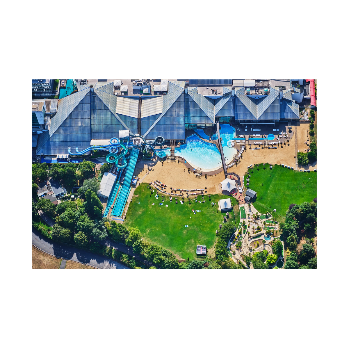 Aerial view of a water park in the Paris area, with blue slides, swimming pools, sun loungers and green lawns; print only