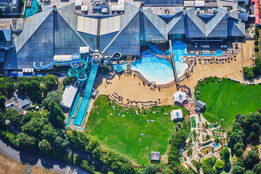 Aerial view of a water park in the Paris area, with blue slides, swimming pools, sun loungers and green lawns; print only