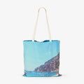 Positano coastal village with turquoise waters and cliffside boats, canvas tote bag by Remy Gerega