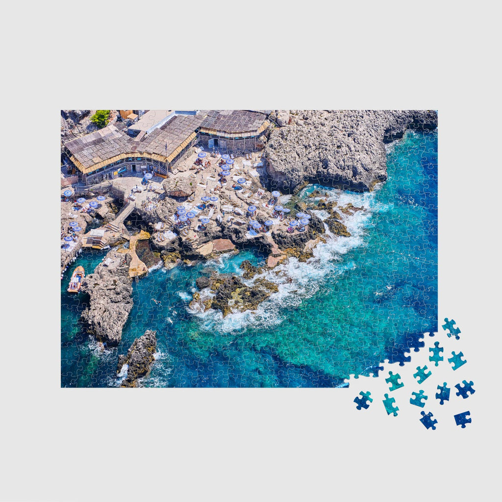 Aerial view of Capri's rocky coastline with turquoise waters and yellow beach umbrellas,500 piece jigsaw puzzle by Remy Gerega