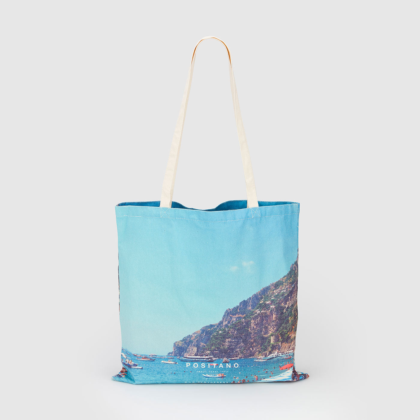 Positano coastal village with turquoise waters and cliffside boats, canvas tote bag by Remy Gerega