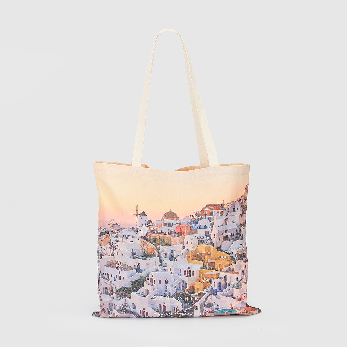 Santorini village sunset view with white buildings and golden domes, canvas tote bag by Remy Gerega.